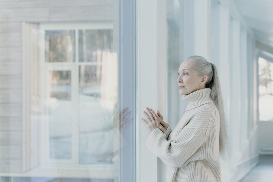 Elderly woman looking out a window, reflecting on what she can no longer do